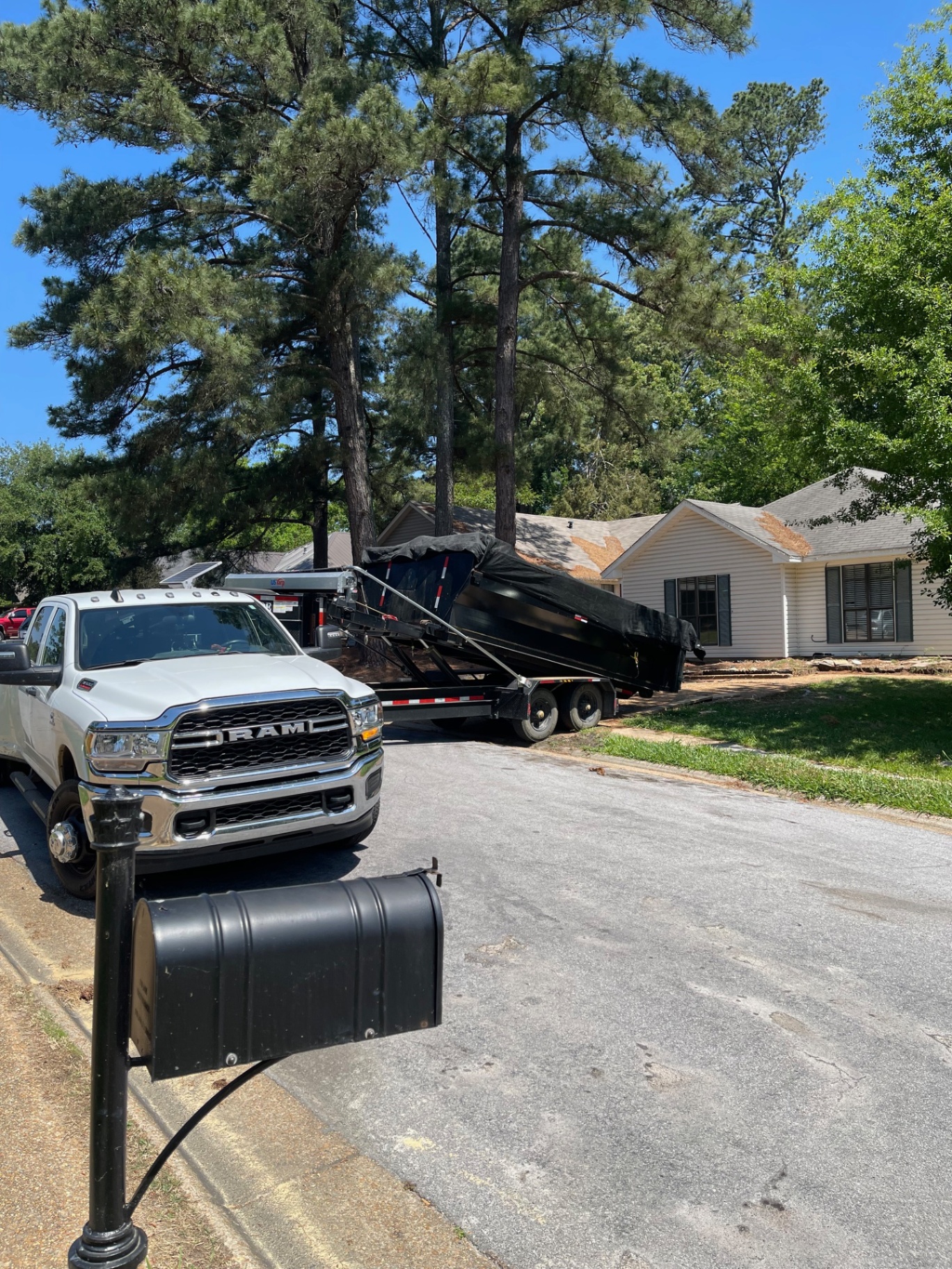 Ram truck delivering a dumpster to a residential street