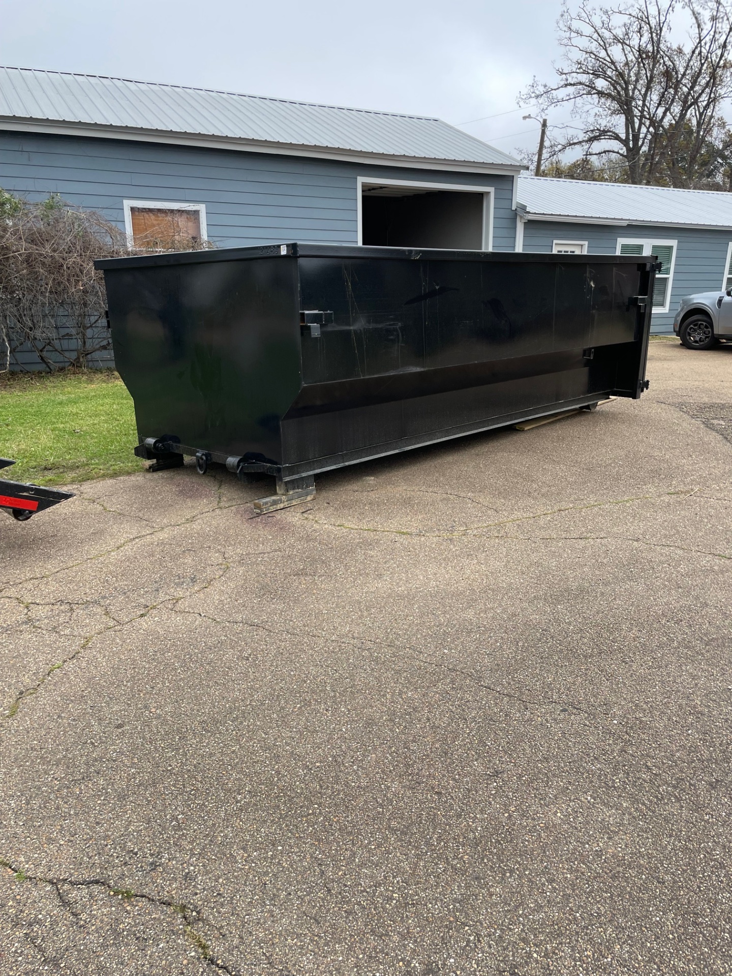 Dumpster on driveway beside blue home